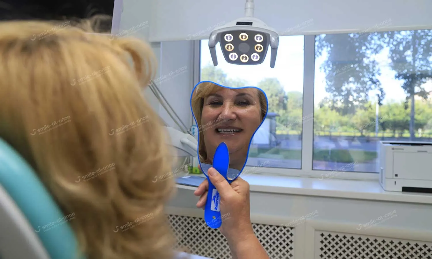Пациентка осматривает свою новую улыбку после имплантации зубов